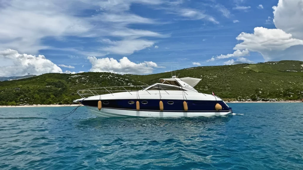 Seitenansicht der Princess V42 auf ruhigem Wasser mit grünen Hügeln im Hintergrund.