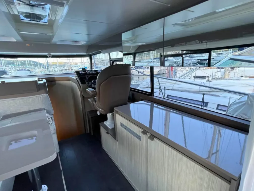 Innenraum der Kommandobrücke einer Cranchi T36 Yacht mit mehreren Sitzen und Panoramafenstern, die den Yachthafen reflektieren.