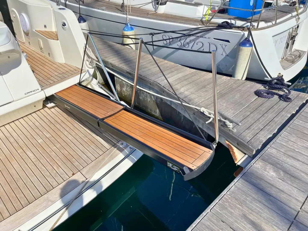 Heckansicht einer am Yachthafen vertäuten Cranchi T36 Yacht, die das Holzdeck mit einer einziehbaren Bordtreppe und umliegenden Booten zeigt.