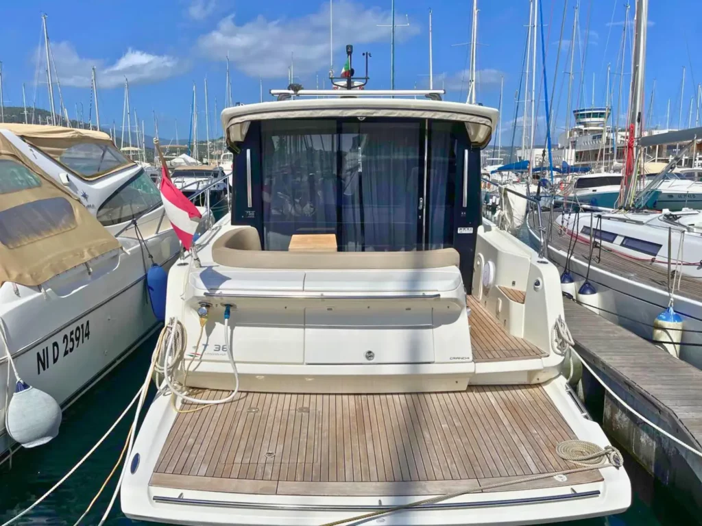 Rückansicht einer Cranchi T36 Yacht, die das Achterdeck und einen geräumigen Sitzbereich unter einem einziehbaren Dach zeigt, vertäut in einem belebten Yachthafen.