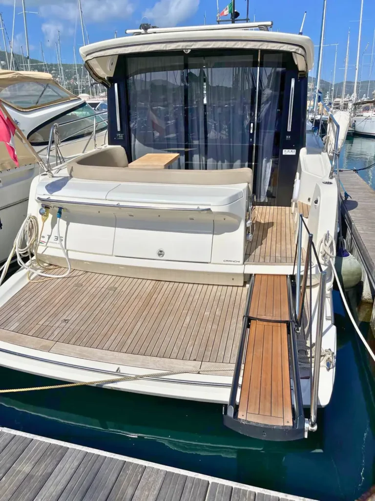 Heckaußenbereich einer Cranchi T36 Yacht mit Außensitzgelegenheiten, einem Holzdeck und Blick auf den umgebenden Yachthafen.