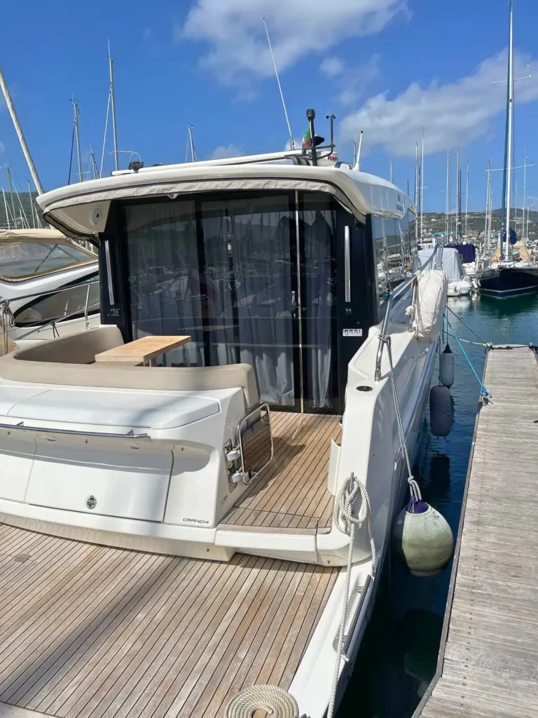 Heckansicht einer am Yachthafen vertäuten Cranchi T36 Yacht mit einem geräumigen Heckdeck und Panorama-Schiebetüren aus Glas.
