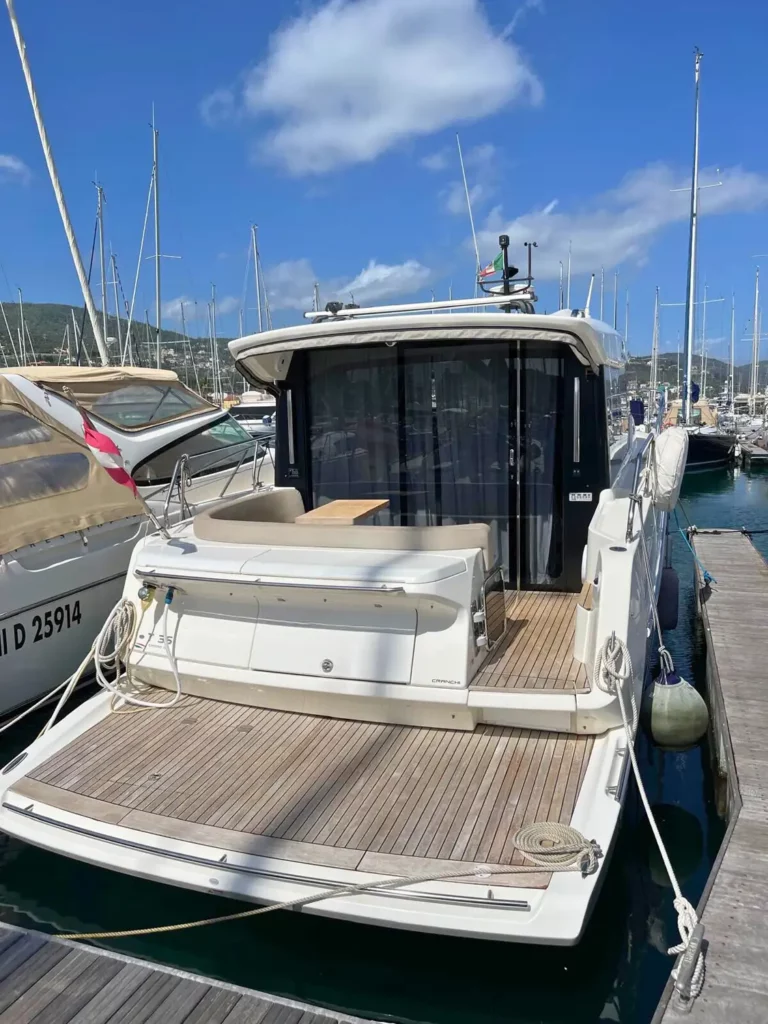 Heckansicht einer am Yachthafen vertäuten Cranchi T36 Yacht mit einem geräumigen Heckdeck und Panorama-Schiebetüren aus Glas.