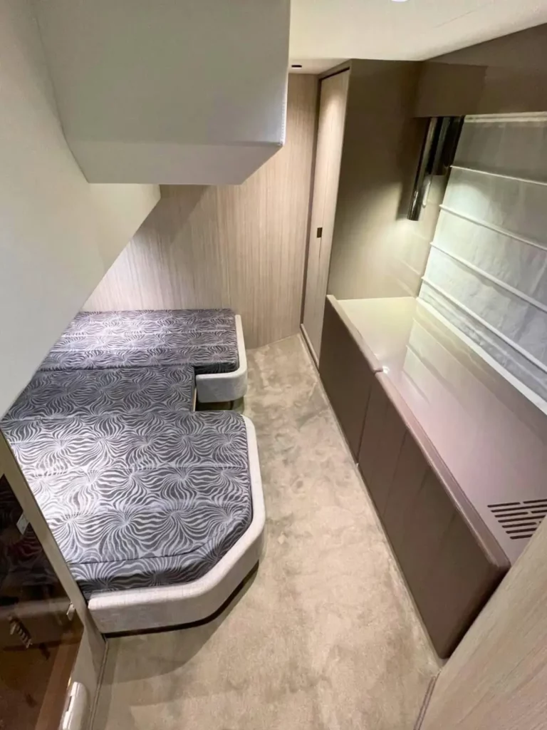 Schlafbereich in einer Cranchi T36 Yacht, der zwei gemusterte Betten in einem kompakten Raum mit Umgebungsbeleuchtung und Holzverkleidung zeigt.