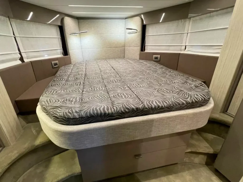 Großes Doppelbett im Hauptschlafzimmer einer Cranchi T36 Yacht mit grau gemusterter Bettwäsche und Umgebungsbeleuchtung sowie reichlich Stauraum.