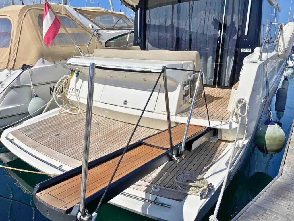 Heckansicht einer am Yachthafen vertäuten Cranchi T36 Yacht mit einem geräumigen Heckdeck,Panorama-Schiebetüren aus Glas und ausgezogener Bordtreppe.