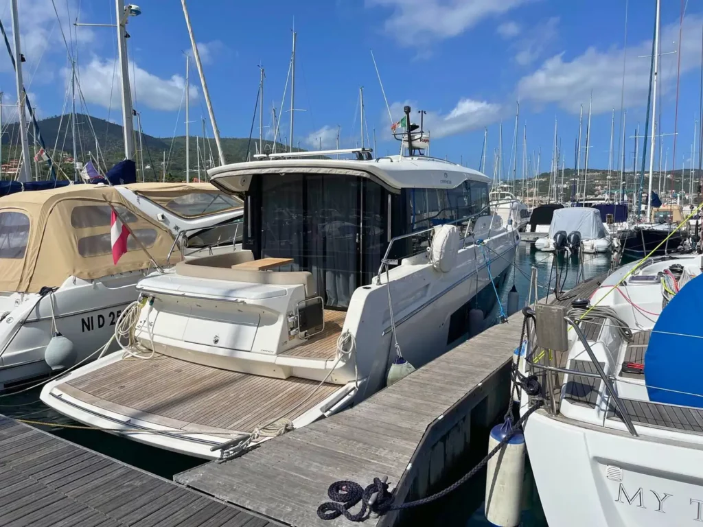 Heckansicht einer am Yachthafen vertäuten Cranchi T36 Yacht mit einem geräumigen Heckdeck und Panorama-Schiebetüren aus Glas.