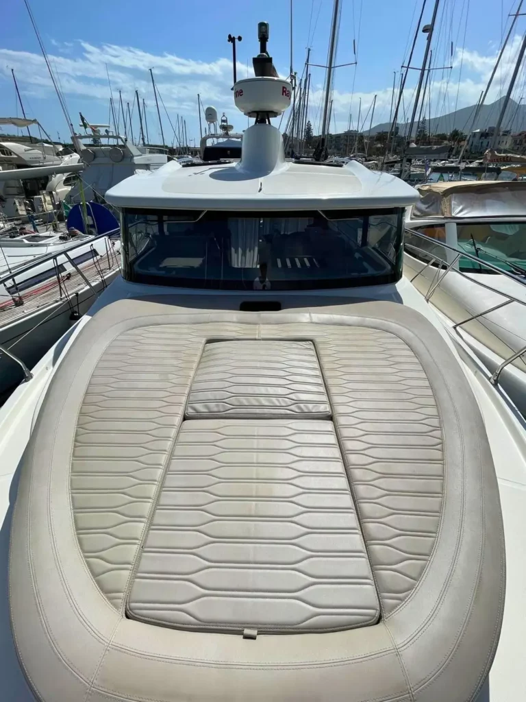Sonnenpolster am Bug einer Cranchi T36 Yacht mit beigen Kissen, positioniert für optimale Entspannung und Sonnenbaden, mit Blick auf den umgebenden Yachthafen.