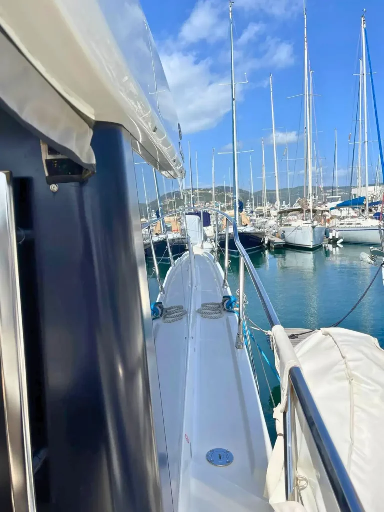 Schmaler Blick entlang der Steuerbordseite einer Cranchi T36 Yacht, die das mit Seilen gesäumte Deck und einen klaren Blick auf den Yachthafen und festgemachte Boote zeigt.