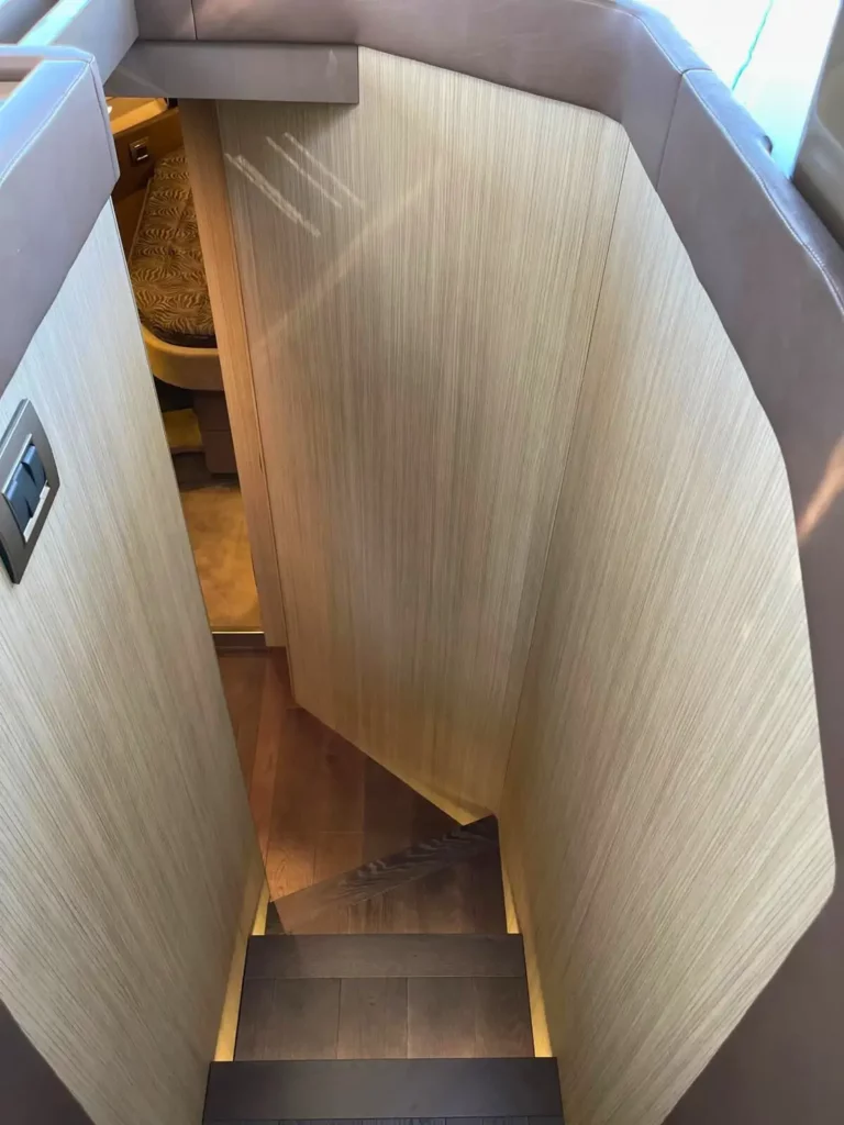 Holztreppe, die zum unteren Deck einer Cranchi T36 Yacht führt, zeigt helle Holzwände und einen Blick in das Innere der Kabine.