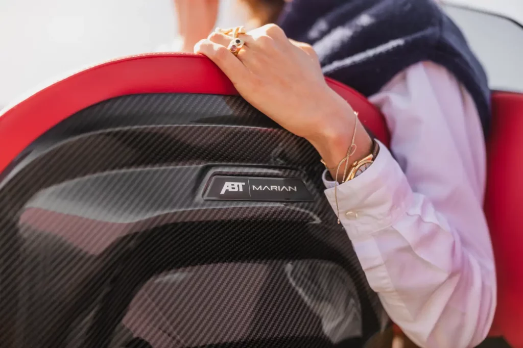 Detailaufnahme einer Hand auf dem Rücken eines Bootssitzes der ABT Marian M 800-R, hervorgehoben durch Karbonfaser-Verkleidung und ein eingelassenes Marian und ABT-Logo, mit einem roten Sitzen.