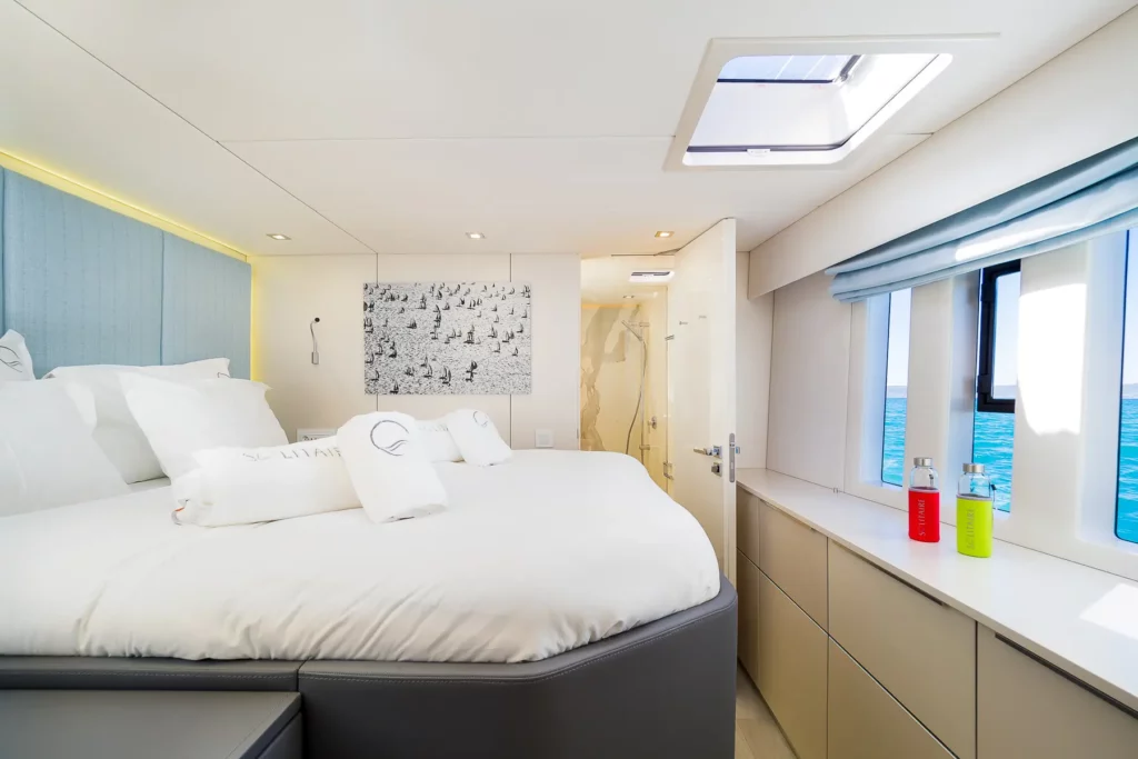 Another elegant bedroom on the Sunreef 50 yacht, featuring a large bed, soft lighting, and an en-suite bathroom, with a view of the sea through the windows.