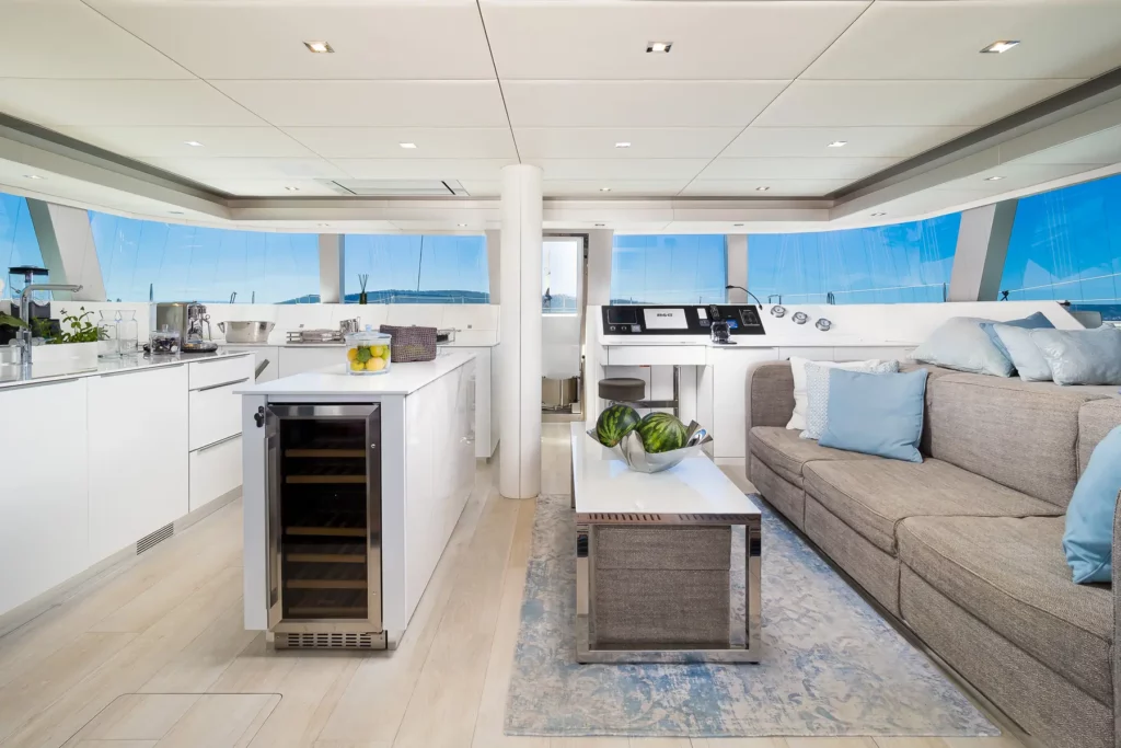 The living area on the Sunreef 50 yacht, showcasing a combination of the kitchen and a comfortable seating space, with panoramic windows offering expansive sea views.