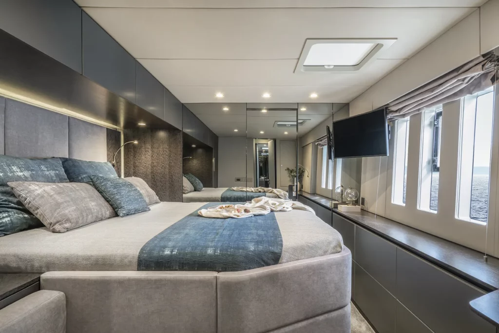 Luxuriöses Schlafzimmer auf der Sunreef 60, mit einem geräumigen Bett, sanfter Beleuchtung und großen Fenstern, die einen malerischen Blick auf das Meer bieten.