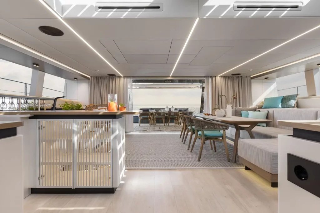 Der Innenraum der Sunreef Power 60P Eco Yacht, mit einem offenen Wohnbereich, der sich nahtlos in einen Außenessbereich erstreckt. Moderne Möbel und dezente Beleuchtung unterstreichen den luxuriösen und umweltfreundlichen Charakter der Yacht.