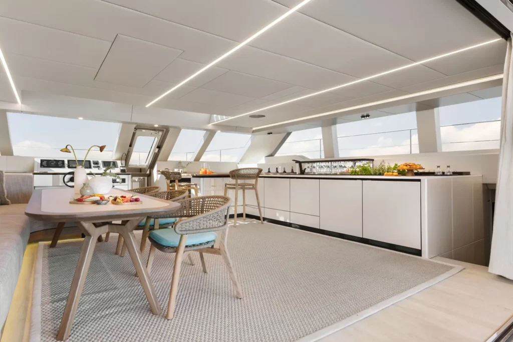 Ein Blick auf die geräumige Küche der Sunreef Power 60P Eco Yacht mit einem modernen Essbereich. Die offene Gestaltung und elegante Ausstattung schaffen eine einladende und nachhaltige Atmosphäre.