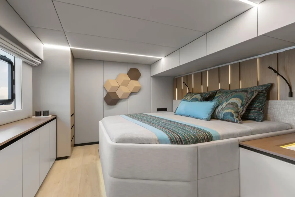 Ein luxuriöses Schlafzimmer auf der Sunreef Power 60P Eco Yacht, das mit einer großen, gemütlichen Liegefläche und stilvollen Wandelementen ausgestattet ist. Die Atmosphäre ist modern, beruhigend und spiegelt die umweltfreundliche Philosophie der Yacht wider.