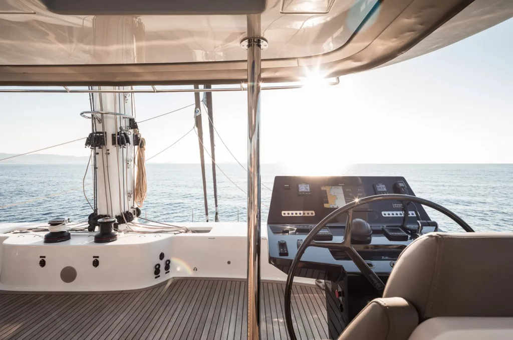 Steuerrad und Navigationsinstrumente auf der Flybridge der Sunreef 70 bei Sonnenaufgang, mit Blick auf das offene Meer.