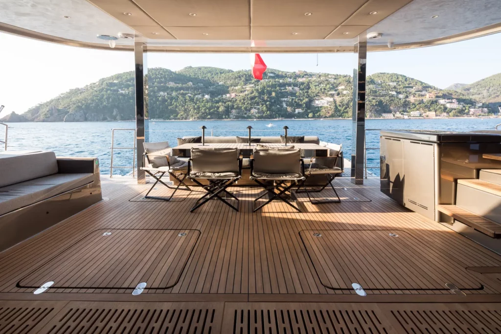 Offener Außenbereich am Heck der Sunreef 70, der einen einladenden Esstisch, Liegen und eine wunderbare Aussicht auf das Meer bietet.