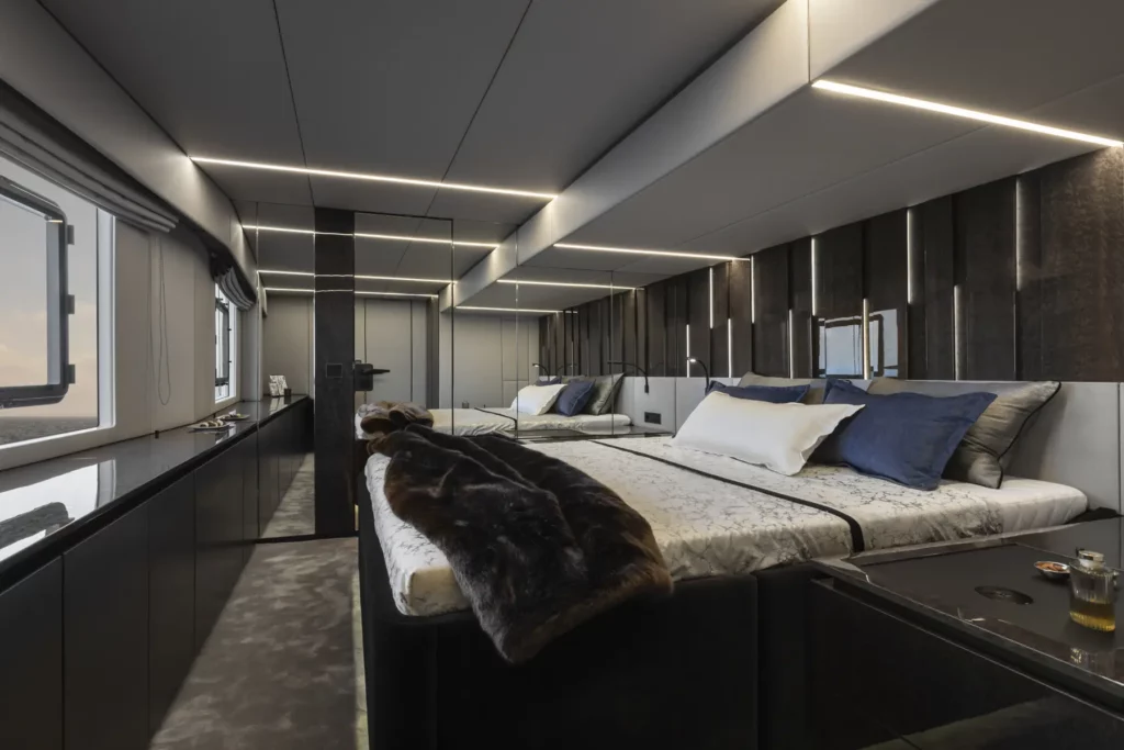 Ein modernes und stilvolles Schlafzimmer auf der 80 Sunreef Power Yacht, mit einem großen Bett, Spiegelwänden, plüschiger Bettwäsche und viel Stauraum, entworfen für Komfort und Entspannung auf See.