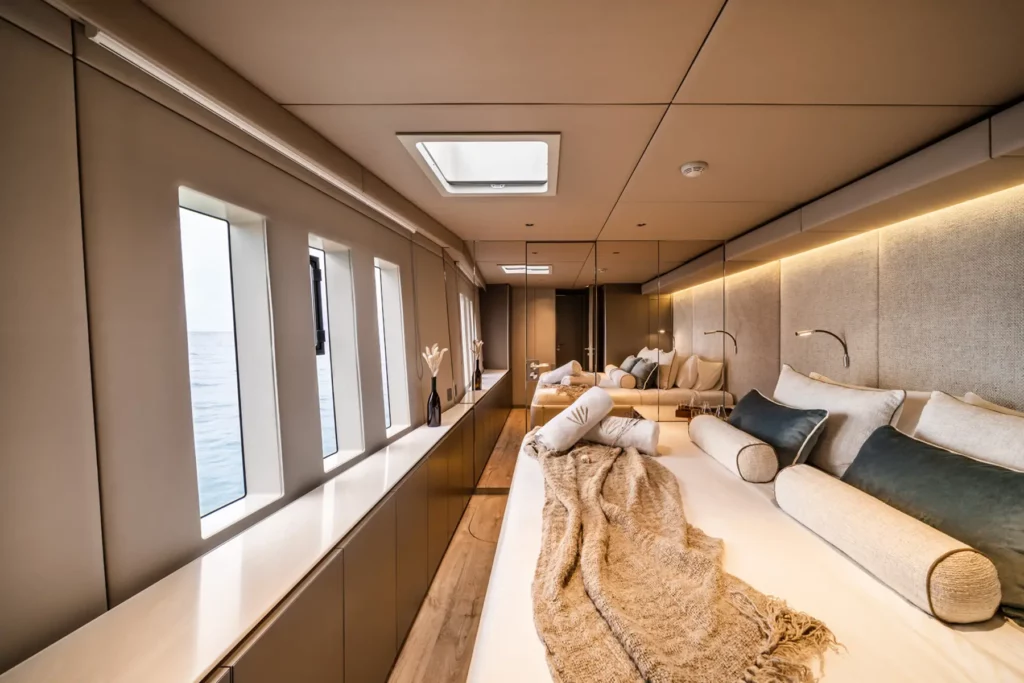 Helles, geräumiges Schlafzimmer auf dem Sunreef 80 Katamaran, mit großen Fenstern, einem gemütlichen Bett und moderner, minimalistischer Einrichtung.