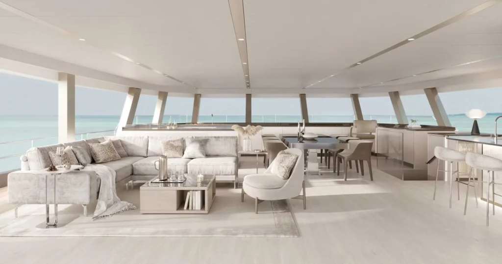 Innenansicht des luxuriösen Wohnbereichs eines Sunreef Supreme Power Eco-Katamarans mit Panoramafenstern, einem großen Sofa, einem Esstisch und einer Bar, alles in hellem, modernem Design gehalten.