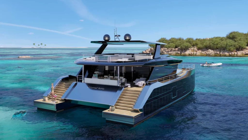 Heckansicht eines Sunreef Supreme Power Eco-Katamarans, der vor einer tropischen Insel ankert, mit Heckgarage und breiten Treppen, die ins Wasser führen.
