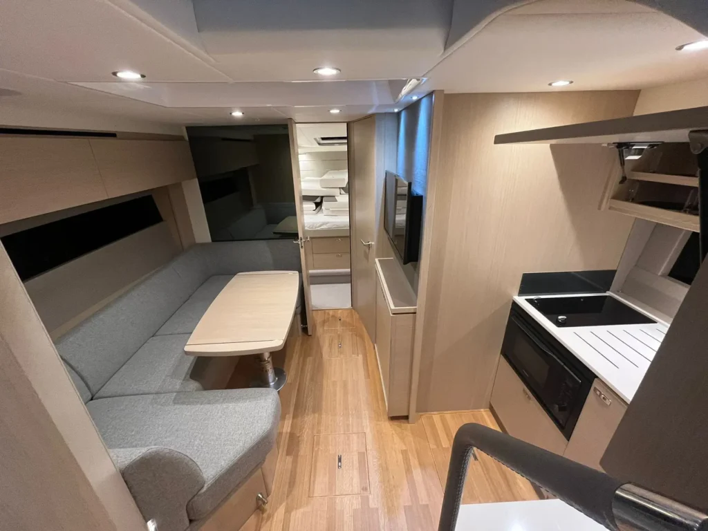 Das Unterdeck der Princess V40 2022 mit einem stilvollen Lounge-Bereich, einem Esstisch und moderner Innenausstattung aus Holz und Stoff.