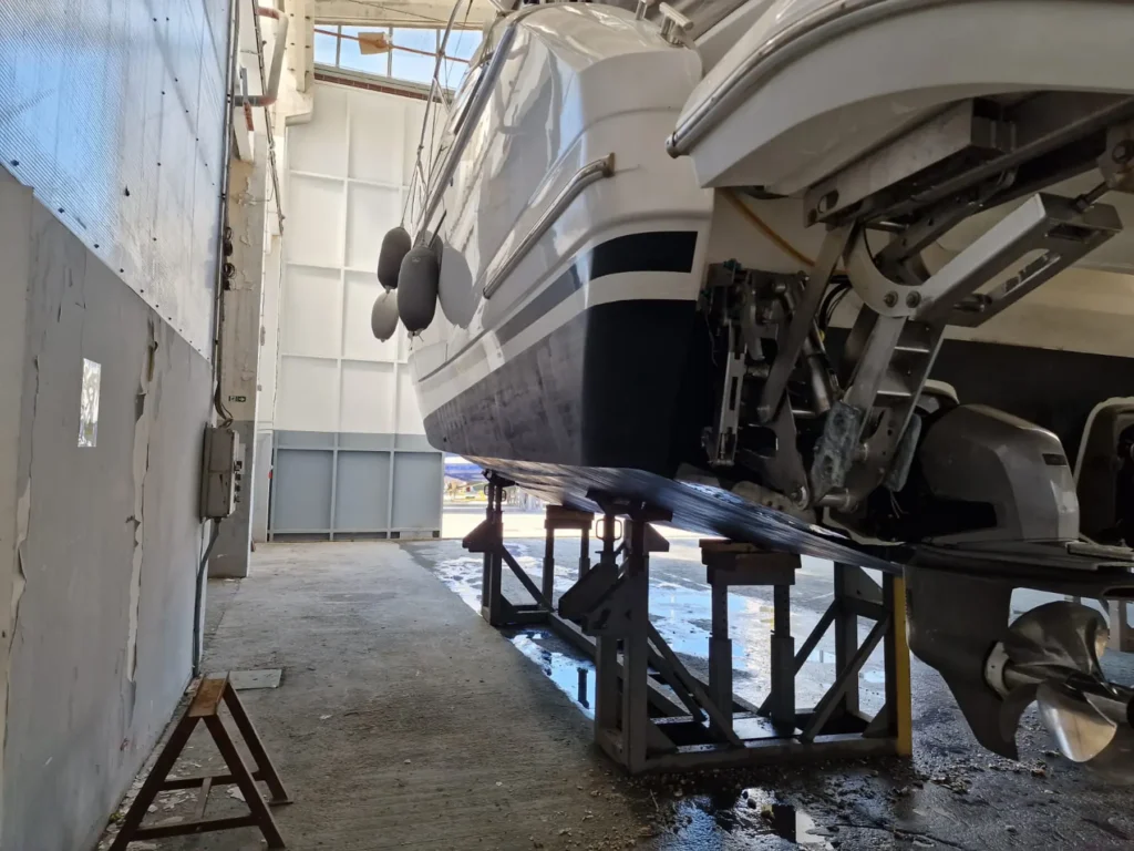 Ansicht des Hecks der Princess V40 2022, die sich in einer Lagerhalle befindet. Detaillierte Darstellung der Motorhalterungen und des unteren Schiffsrumpfs.